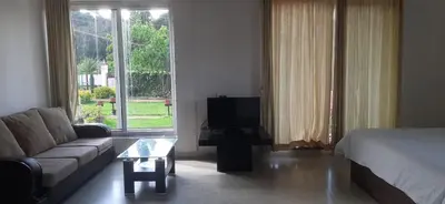 a living room with a couch and a bed and a tv at Velus Bungalow Ooty in Ooty