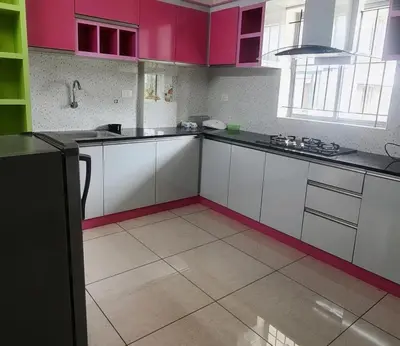 a kitchen with white counters and pink cabinets at MAYPORT HERITREAT in Alwaye