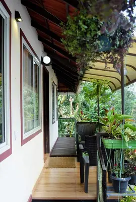a porch of a house with a table and chairs at Raymond's Holiday Homes in Vythiri