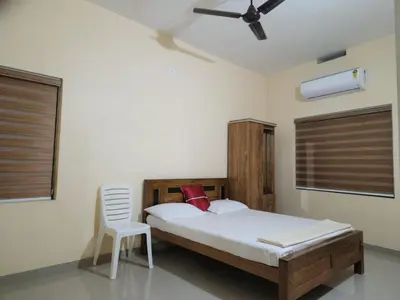 a bedroom with a bed and a chair in it at Fathima Apartments in Iritti