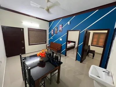 a bathroom with a table and a sink and a bedroom at Fathima Apartments in Iritti
