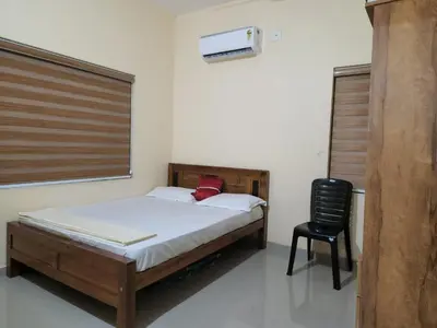 a bedroom with a bed and a black chair at Fathima Apartments in Iritti