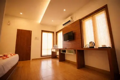 a room with a bed and a desk with a television at Oxyvalley Resort in Attappādi