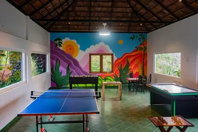 a room with ping pong tables and a mural at Oxyvalley Resort in Attappādi