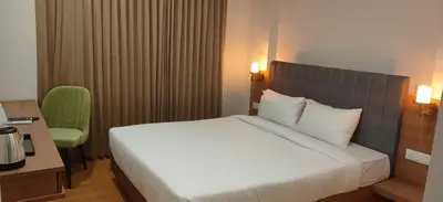 a bedroom with a white bed and a green chair at HILUX COURTYARD in Palakkad