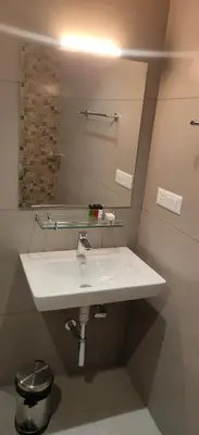 a bathroom with a white sink and a mirror at HILUX COURTYARD in Palakkad