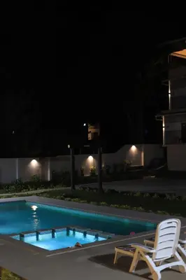 a swimming pool at night with a white chair and avisorvisorvisor at Seeheim Resorts in Athirappilly