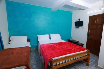 a bedroom with two beds and a blue wall at Seven Endue Cottages in Ooty