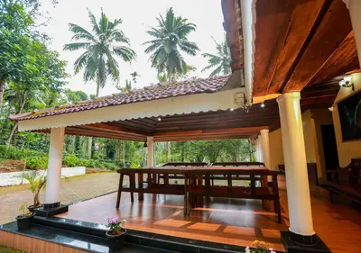 a pavilion with a wooden deck with palm trees in the background at Chandragiri Heritage Bungalow and Cottages in Vaduvanchal