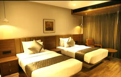 a hotel room with two beds and a table at Crystal Suites in Badagara