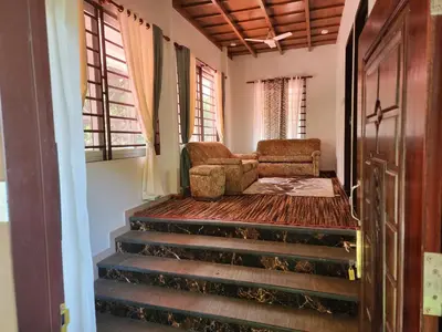 a room with stairs and a chair and windows at VanaJyotsna Forest Home in Marayoor