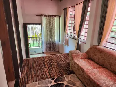 a living room with a couch and two windows at VanaJyotsna Forest Home in Marayoor
