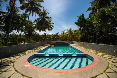a swimming pool with chairs in a resort at Ibex River Resort, Pollachi in Coimbatore