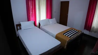 two beds in a small room with red curtains at Thas apartment near rajagiri hospital in Alwaye