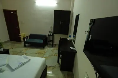 a hotel room with a bed and a chair at Aldora Airport Residency in Nedumbassery