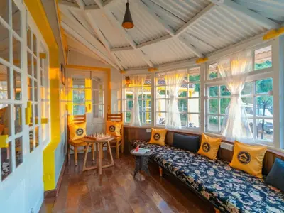 a living room with a couch and some windows at The Hosteller Ooty in Ooty