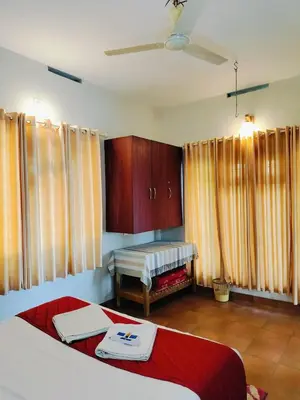 a bedroom with two beds and a table and curtains at Karapuzha Water Scapes Wayanad in Wayanad