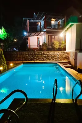 a swimming pool in front of a house at night at Karapuzha Water Scapes Wayanad in Wayanad