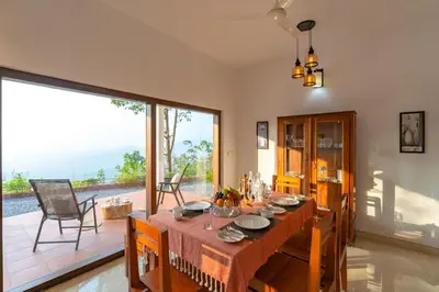a dining room with a table and a large window at La Grove 2BHK with Stunning View - Kannur in Wayanad