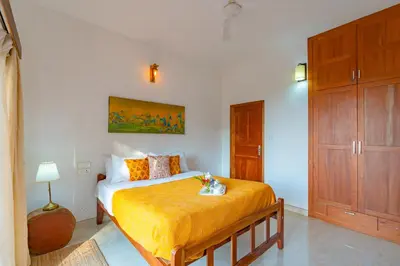 a bedroom with a bed with orange sheets and a cabinet at La Grove 2BHK with Stunning View - Kannur in Wayanad