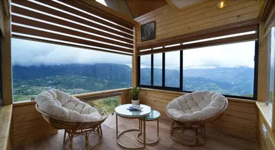 two chairs and a table in a room with windows at Vrindhavan Farm Suites in Kanthalloor