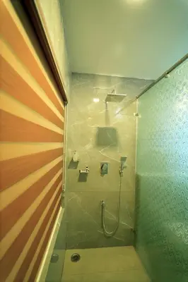 a bathroom with a shower with a glass door at Vrindhavan Farm Suites in Kanthalloor