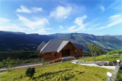 a cabin on a hill with mountains in the background at Vrindhavan Farm Suites in Kanthalloor