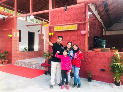a family posing in front of a red building at Coorg Happy Estate Stay in Madikeri