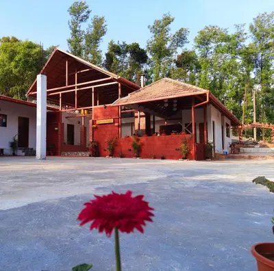 a red flower in front of a building at Coorg Happy Estate Stay in Madikeri
