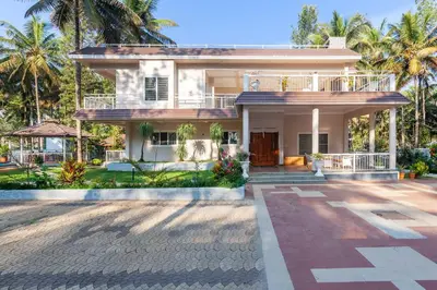 a house with palm trees in the background at Bask In The Greens Coorg with Private Pool - Pet Friendly - Complimentary Breakfast in Madikeri