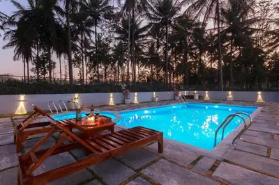 a swimming pool with a table and a bench next to it at Bask In The Greens Coorg with Private Pool - Pet Friendly - Complimentary Breakfast in Madikeri