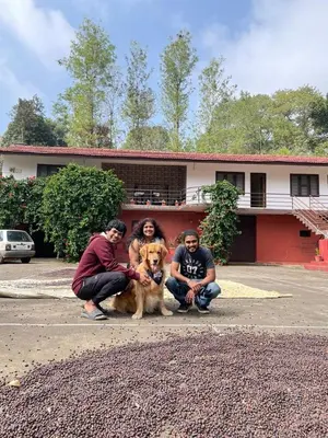 three people and a dog in front of a house at Shree Raksha Homestay in Gonikoppal