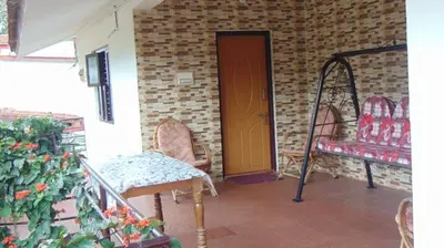 a porch with two chairs and a wooden door at Shree Raksha Homestay in Gonikoppal