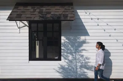 a woman walking in front of a house at The Little Acres Cherai in Vypīn