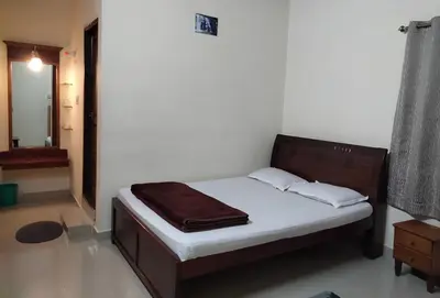 a small bedroom with a bed with white sheets at Prashanth Family Homestay in Madikeri