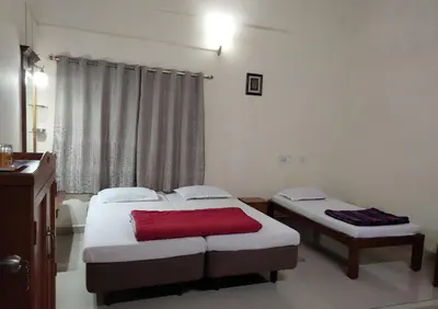 two twin beds in a room with a window at Prashanth Family Homestay in Madikeri