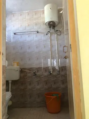 a bathroom with a toilet and a light on the wall at Single room Homestay Second floor in Palani