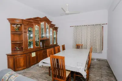 a dining room with a table and a wooden cabinet at Alite Posh 4 BHK Villa in Thrissur Town in Trichūr