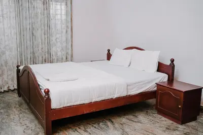 a bed with white sheets and a wooden frame and a table at Alite Posh 4 BHK Villa in Thrissur Town in Trichūr