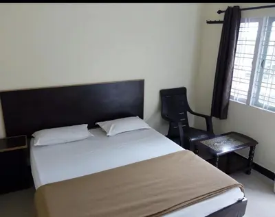 a bedroom with a bed and a chair and a window at The Valley Villa in Kotagiri