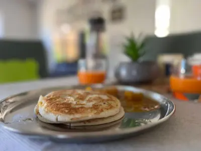 a plate of food with pancakes on a table at Zyamadhari in Mananthavady