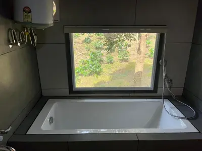 a bath tub in a bathroom with a window at Zyamadhari in Mananthavady