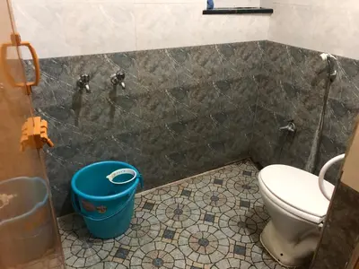 a bathroom with a toilet and a bucket at Aishwarya Nivas in Palani