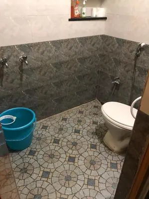a bathroom with a toilet and a blue bucket at Aishwarya Nivas in Palani