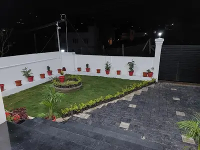 a garden with potted plants on a white wall at Kodai Diva Inn - Home Stay in Kodaikānāl