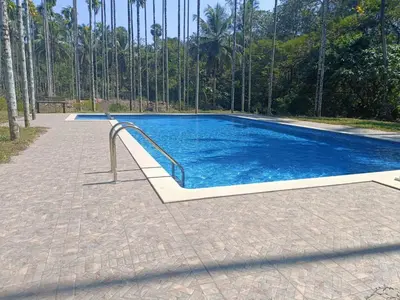 a swimming pool with a metal handrail in front of trees at Kalappura Farm House Heritage in Ottappālam
