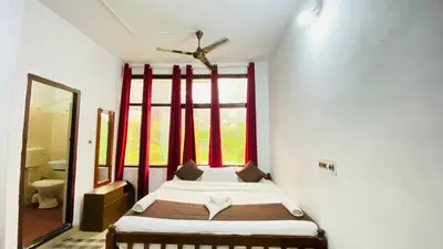 a small bedroom with a bed and a window at Hotel Caveri Inn in Madikeri