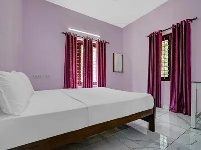 a white bed in a room with red curtains at Shalom Palace Residency in Neriyamangalam