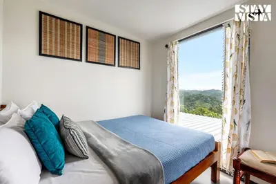 a bedroom with a bed and a large window at StayVista at Griha Sankalpa with Mountain View, BBQ Wayanad in Koroth