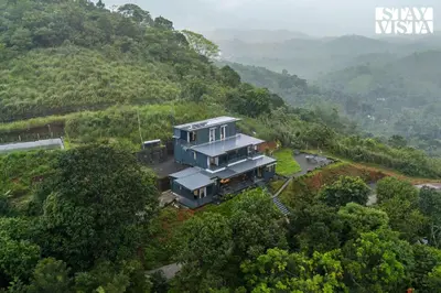 an aerial view of a house on a hill at StayVista at Griha Sankalpa with Mountain View, BBQ Wayanad in Koroth